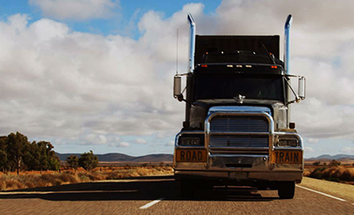 A road train truck drives down a remote road.