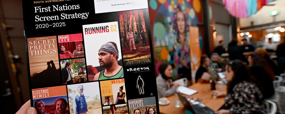 Hand holding the SAFC's First Nations Screen Strategy at an event, photo by Naomi Jellicoe