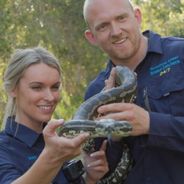 A woman and a man holding a snake