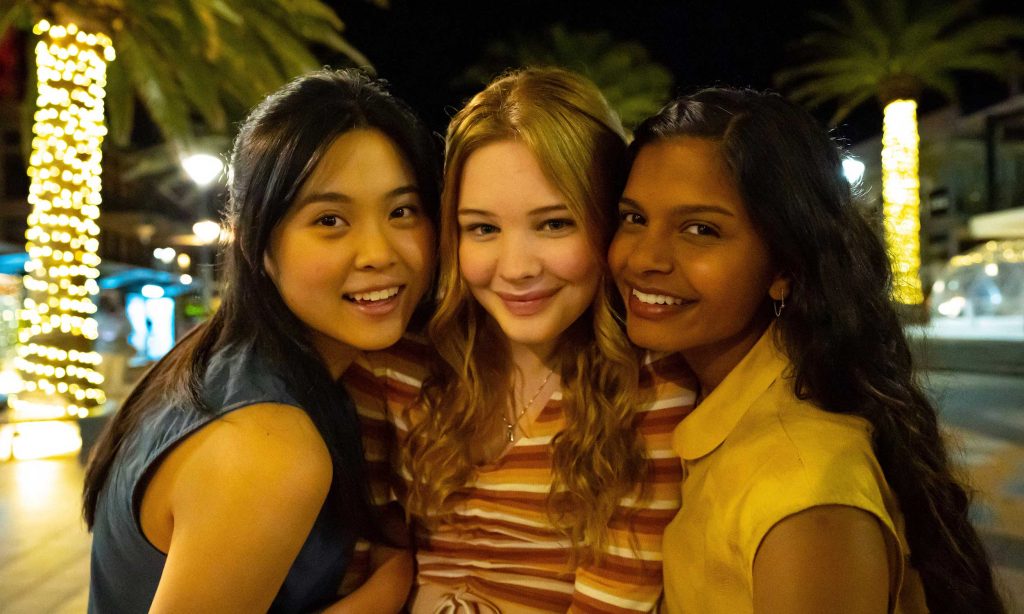 Three teenage girls standing closely in a line, smiling