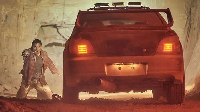 A still from Firebite of Rob collins and a car's tail lights in a cave