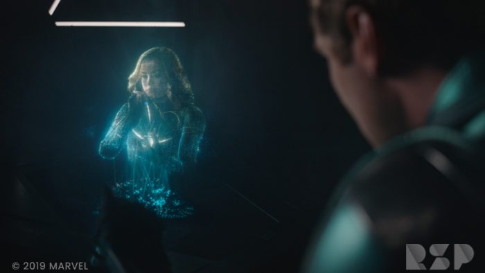 A man looks at a hologram of a woman in a dark room