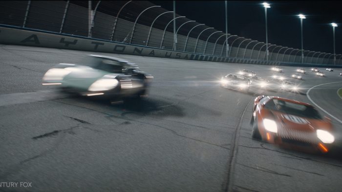 A still of Ford V Ferrari - cars on a racetrack at night.