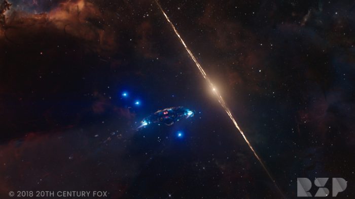 A space ship flies in front of starry galaxies.