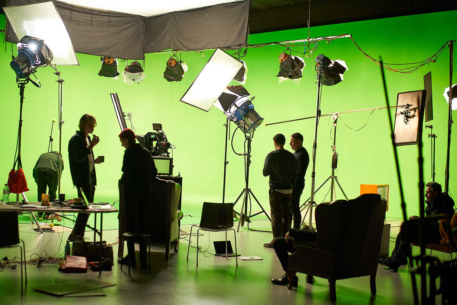 Film crew on set with equipment in front of a green screen