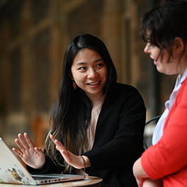 Two young women sitting in front of a laptop talking