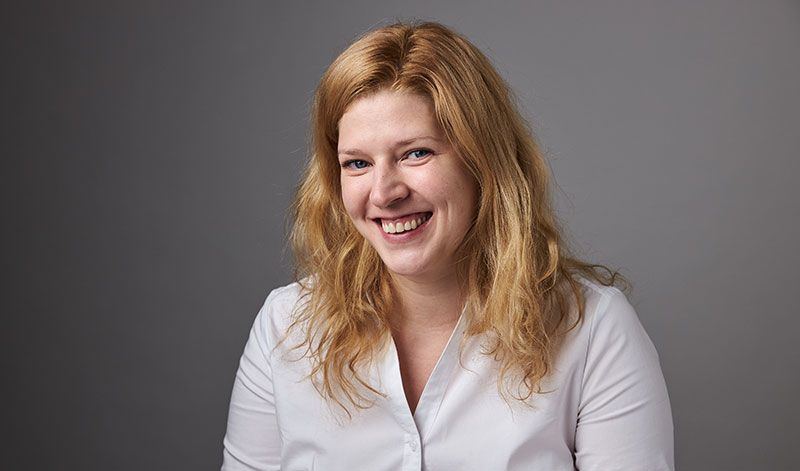 Headshot of a woman wearing a white shirt against a grey background