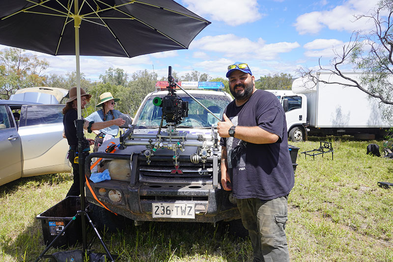 BTS on The Red - attachment Travis Akbar standing with Camera on prop vehicle, image supplied