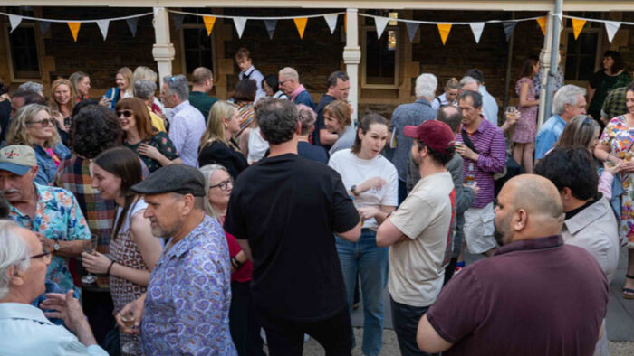 A large crowd gather in an old stone courtyard.