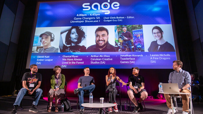 A panel of SA video game developers sit in front of a cinema screen.