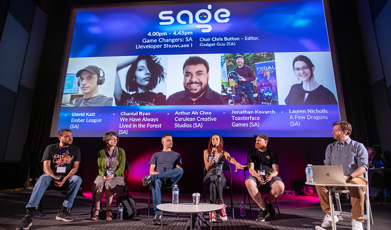 A panel of SA video game developers sit in front of a cinema screen.