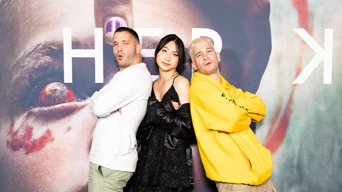 Michael Philippou, Sora Wong and Danny Philippou pose in front of a media wall.