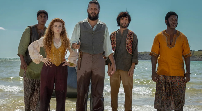 Five people stand on a beach.