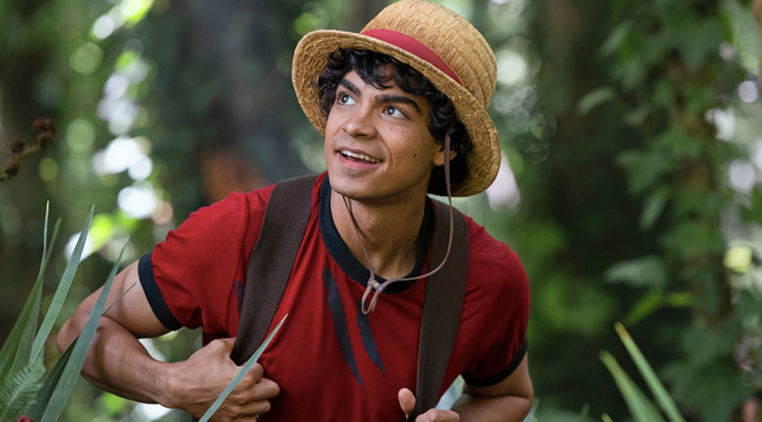 A young man in a jungle environment wears a straw hat and backpack.