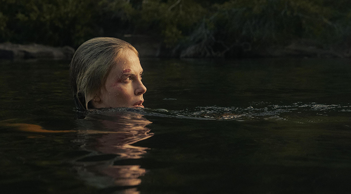 Charlize Theron in APEX swims in a body of water. Only her head is visible.