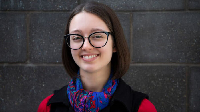 South Australian filmmaker Jasmin Watkins stands in front of a dark grey wall.